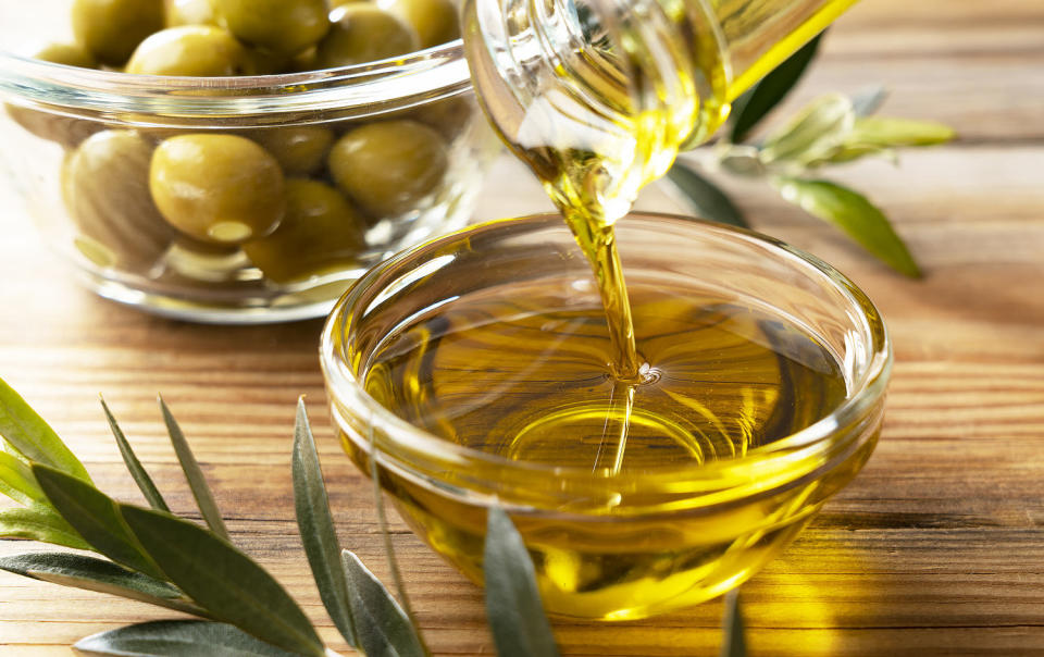 Olive oil in a glass bowl set against a wooden background (Getty Images)