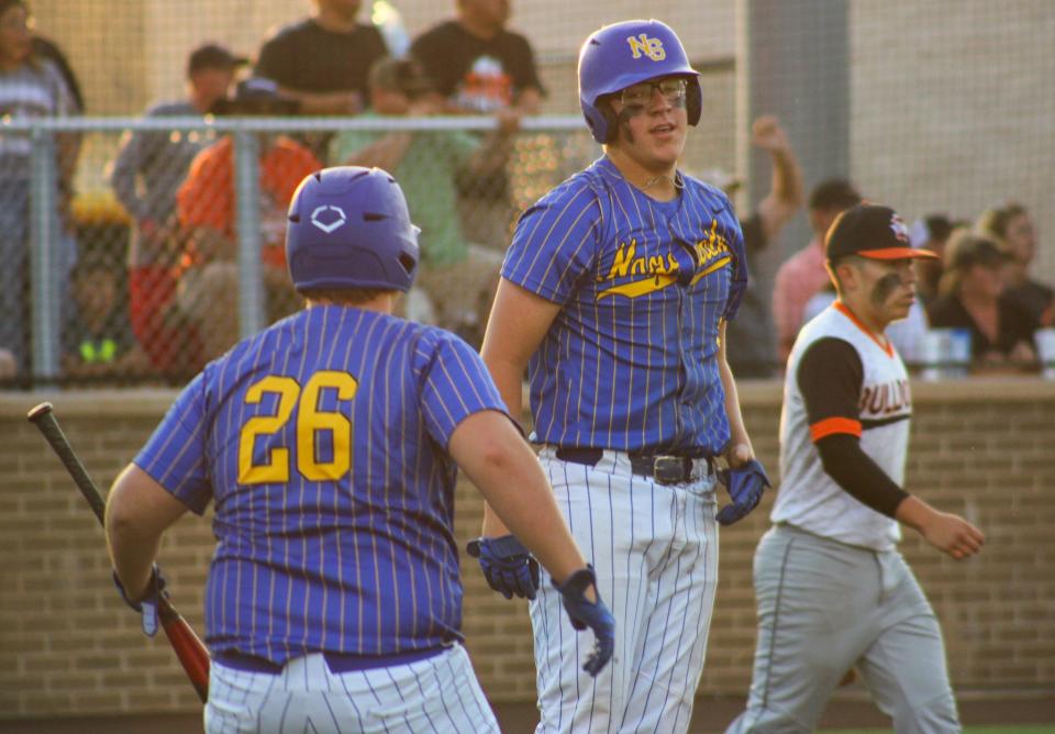 Nazareth's Trent Gerber is welcomed by Brett Young (26) after scoring the tying run during the first game of the Region I-1A baseball championship series in Woodrow on Friday, May 27, 2022.