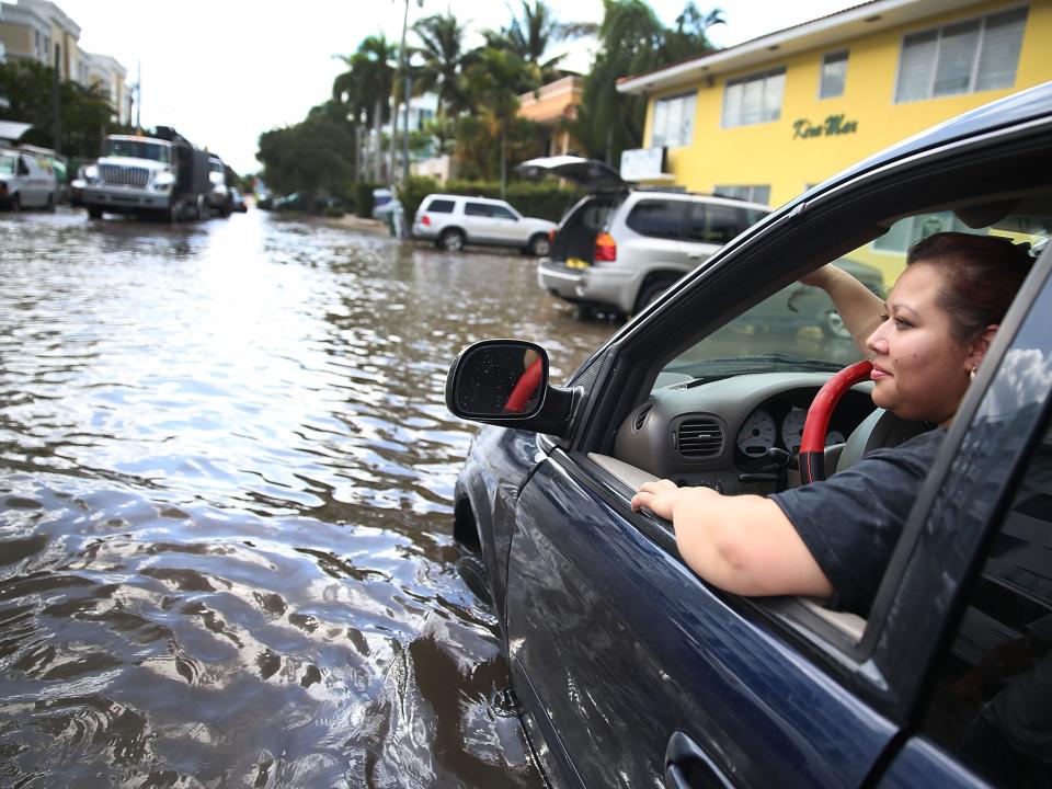Woman drives her car in a flooded road in Florida.