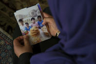 In this Aug. 20, 2018, photo, Meripet, 29, holds on to a photograph of her children in Istanbul, Turkey. Meripet came to Turkey in February 2017 to visit her sick father, leaving four children behind, her oldest son Abdurahman, 8, daughter Adile, 6, son Muhemmed, 4, and son Abdulla, 3. While in Turkey, she heard Uighur passports were being seized and that people who had gone abroad were being taken to reeducation – so she stayed in Turkey, giving birth to Abduweli. She hasn't seen her other four children since, and heard they were taken to a live-in kindergarten in Hotan, China. (AP Photo/Dake Kang)