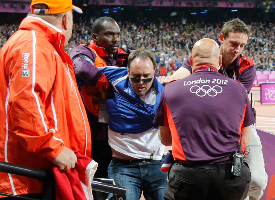 BOTTLE THROWER: A spectator is detained by security after a beer bottle was thrown on to the track during the start of the men's 100 metres final, on Day 9 of the London 2012 Olympic Games at the Olympic Stadium on August 5, 2012 in London, England. (Photo by Chris Helgren - IOPP Pool /Getty Images)