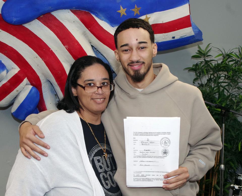 Nancy Demecedo-Fernandes, of Brockton, stands with her son Nicalas, who holds a contract for an Olympic Scholarship that he signed at the Brockton Cape Verdean Association on Monday, April 11, 2022. Nicalas Fernandes is a competitive Taekwondo martial artist who hopes to qualify for the 2024 Summer Olympics taekwondo competition in Paris.