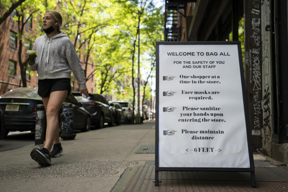 A pedestrian passes a storefront sign that lists COVID-19 protective protocols required for entry in the retail shopping district of the SoHo neighborhood of the Manhattan borough of New York, Friday, May 14, 2021. Gov. Andrew Cuomo has yet to say whether he will change his state’s mask mandate in light of new federal guidance that eases rules for fully vaccinated people. (AP Photo/John Minchillo)