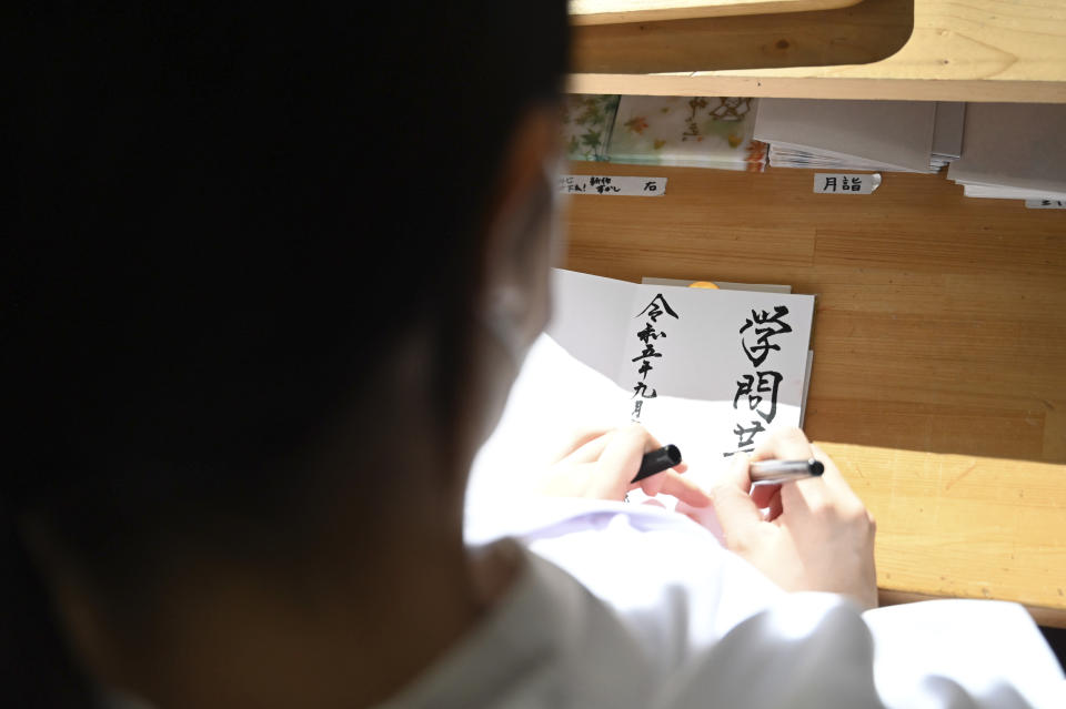 A shrine maiden prepares Goshuin, a seal stamp certifying her visit that comes with elegant calligraphy and the season’s drawings, at Onoterusaki Jinja in Tokyo, on Sept. 18, 2023. The popularity of Goshuin stamps and visits to spiritual spots like shrines and temples is not a show of faith, experts say, but instead suggests people feel an affinity for the traditions without a need to be deeply involved. (AP Photo/Ayaka McGill)