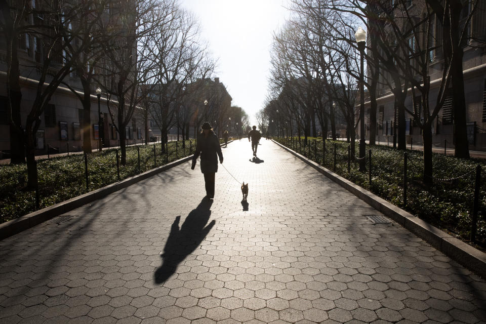 A woman walks her dog on the Columbia University campus, Monday, March 9, 2020, in New York. The Ivy League school is canceling two days of classes this week because a person at the New York school is under quarantine from the rapidly spreading coronavirus, according to university president Lee Bollinger. (AP Photo/Mark Lennihan)