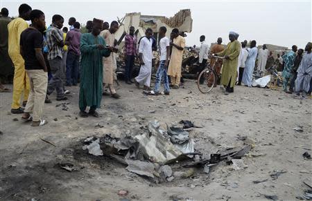 A man takes a picture of a crater after an explosion of one of two vehicles laden with explosives in Ajilari-Gomari near the city's airport, in Maiduguri March 2, 2014. REUTERS/Stringer