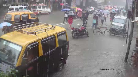 People walk under umbrellas during heavy rains in Parel neighbourhood of Mumbai, India, August 29, 2017 in this still image obtained from a CCTV camera. TWITTER/@VIVEK_J_SINGH via REUTERS