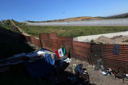 Mexican Carlos, 27, who says that he was deported from the United States, heats up tortillas at his house near the double fence that separates Mexico and the United States, in Tijuana, Mexico. REUTERS/Edgard Garrido