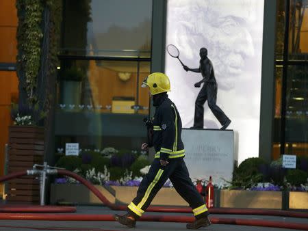 A fireman walks past the statue of Fred Perry after a fire inside Centre Court in Wimbledon at the end of play during the Tennis Championship, in London, 1 July, 2015. REUTERS/Henry Browne