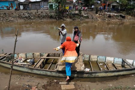 Women board a small boat used as a ferry to cross the Citarum river south-east of Bandung, West Java province, Indonesia, February 8, 2018. REUTERS/Darren Whiteside