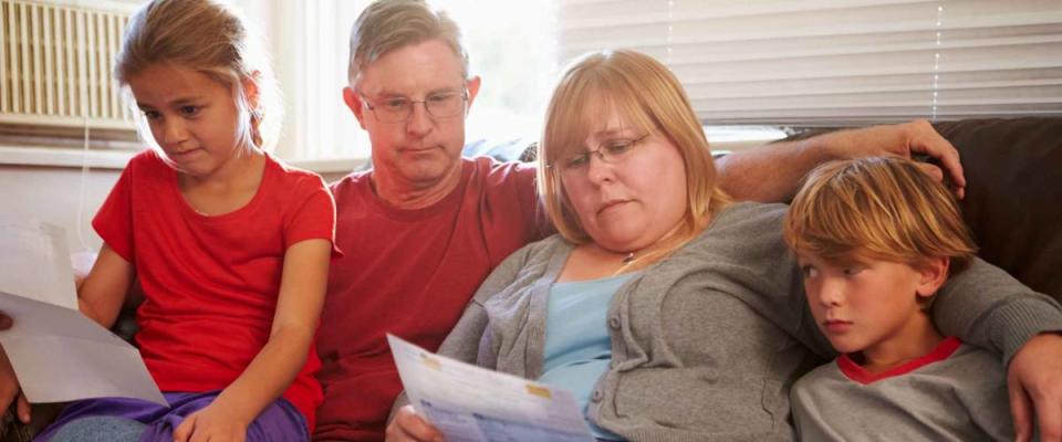 Unhappy Family Sitting On Sofa Looking At Bills