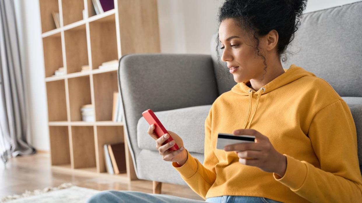 young adult african american girl sitting indoors doing mobile payment online