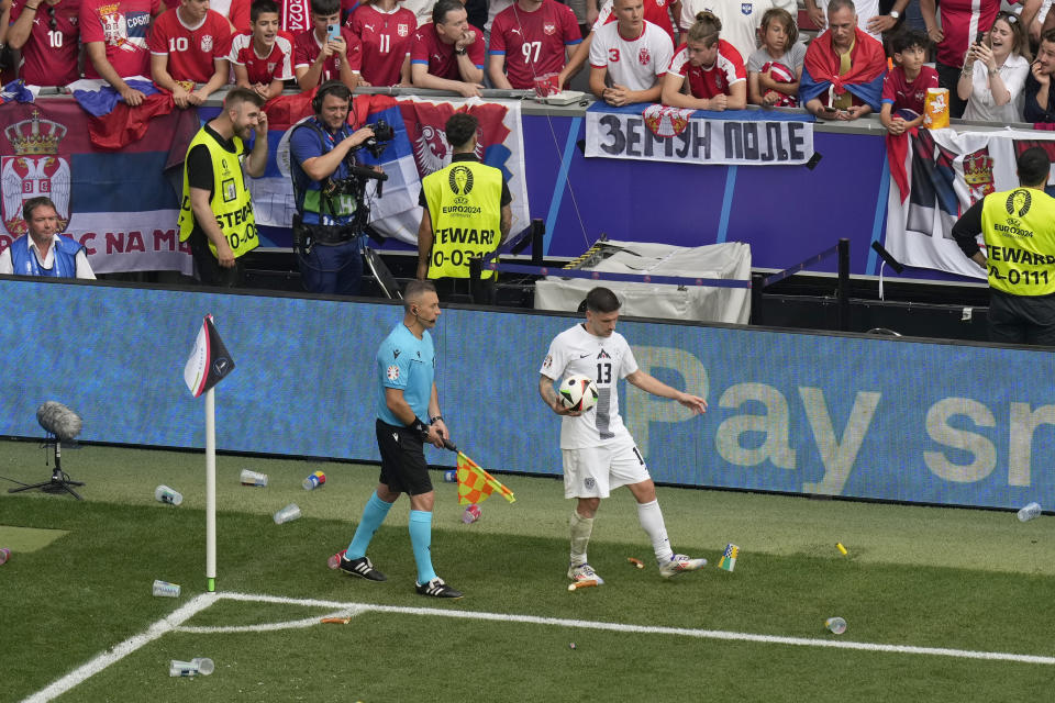 Slovenia's Erik Janza kicks away food and plastic cups thrown from the stands during a Group C match between Slovenia and Serbia at the Euro 2024 soccer tournament in Munich, Germany, Thursday, June 20, 2024. (AP Photo/Ariel Schalit)