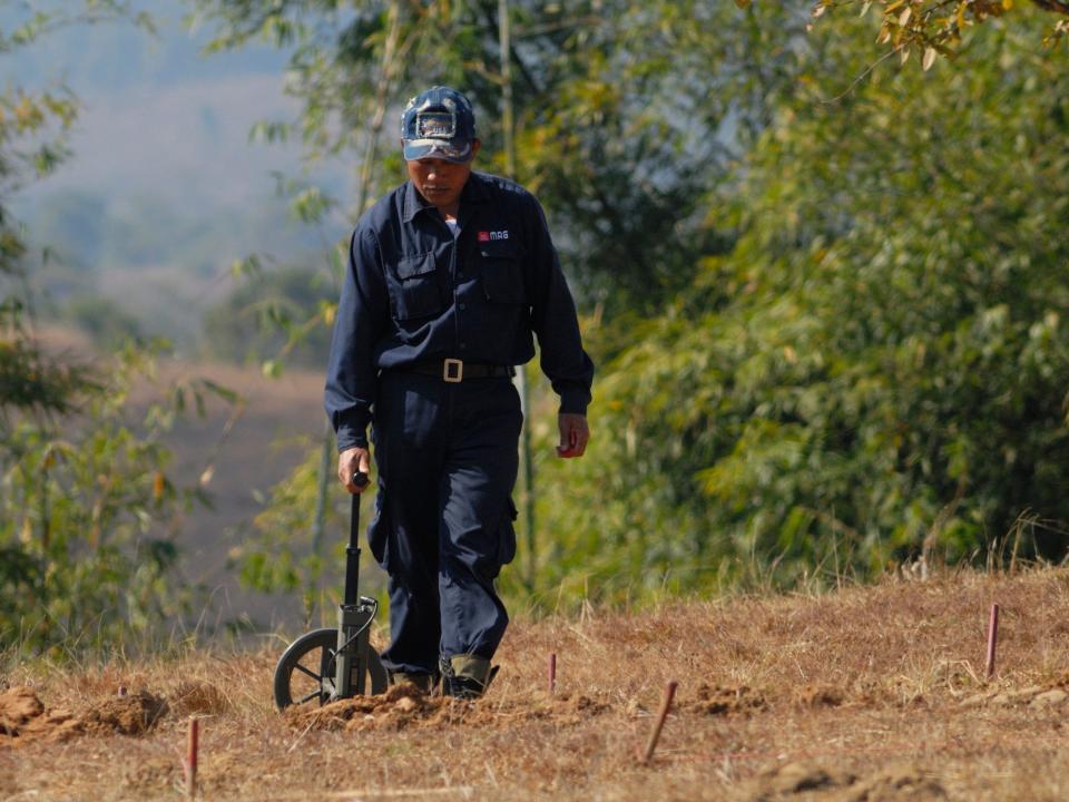 A worker uses a metal detector to search for bombs in Laos.