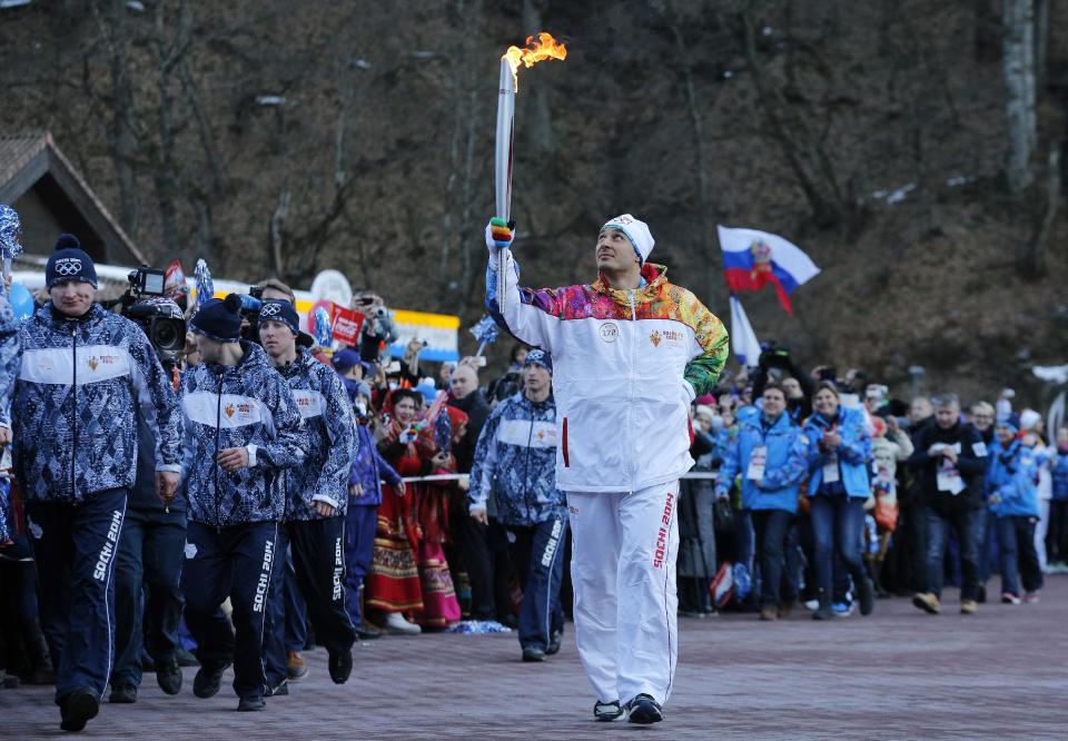 Alexey Voyevoda, a former Olympic bobsledder, who won silver in the 4-man bobsled in Turin in 2006, carries the Olympic torch as it makes it's way throughout the streets of the Rosa Khutor ski resort in Krasnaya Polyana, Russia at the Sochi 2014 Winter Olympics, Wednesday, Feb. 5, 2014. (AP Photo/Christophe Ena)