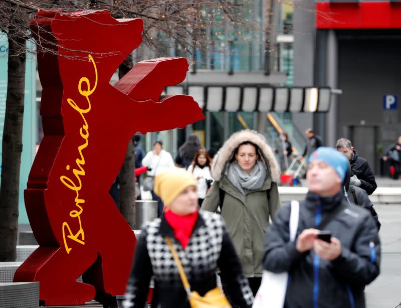 Pedestrians walk past the mascot of the upcoming 70th Berlinale International Film Festival in Berlin