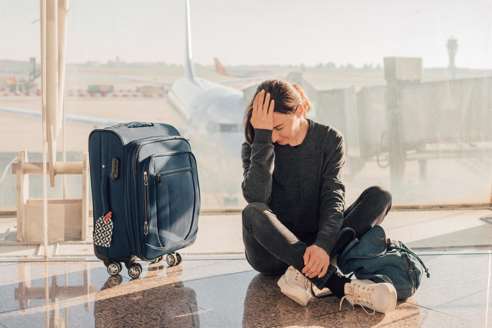 Sad (tired) woman sitting in the airport - missed or cancelled flight concept.