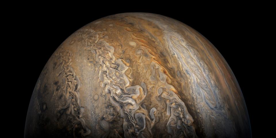 jupiter planet rising in the darkness with swirling bands of orange white purple brown