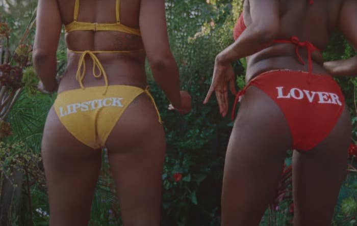 Two people in bikinis. The person's on the left has a bikini bottom that says "lipstick" and the person on the right has a bikini bottom that says "lover"