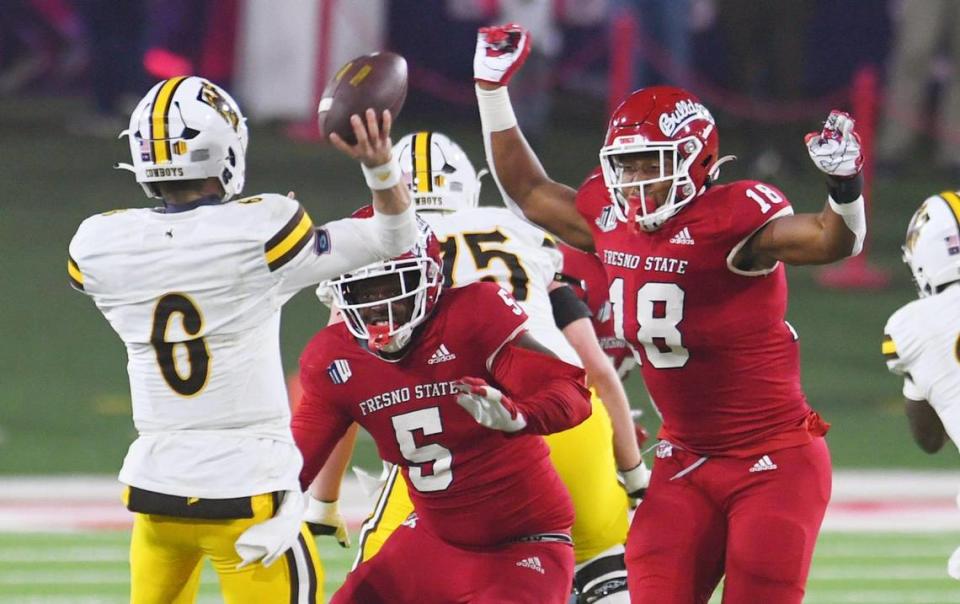 Fresno State’s Devo Bridges, center, and Isaiah Johnson, right, pressure Wyoming quarterback Andrew Peasley, left, in game action Friday, Nov. 25, 2022 in Fresno. The Bulldogs led 23-0 at halftime. ERIC PAUL ZAMORA/ezamora@fresnobee.com