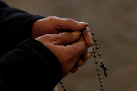 FILE PHOTO: A man holds a rosary during Sunday service at a makeshift, tin-roofed church in Youtong village, Hebei Province, China, December 11, 2016. REUTERS/Thomas Peter/File Photo