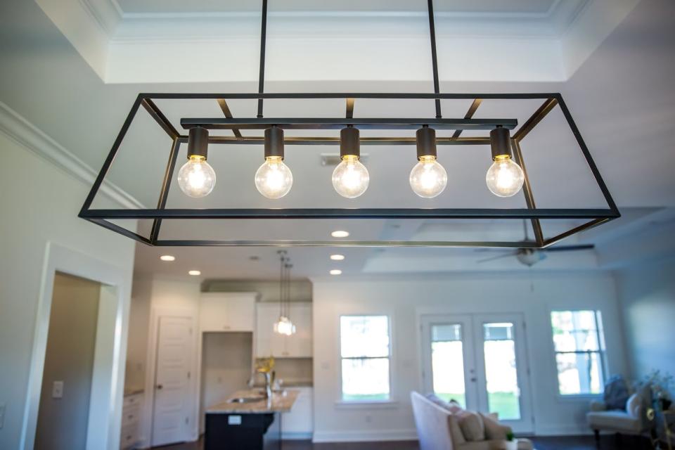 Black metal iron farmhouse chandelier lighting fixture hanging in a dining room.