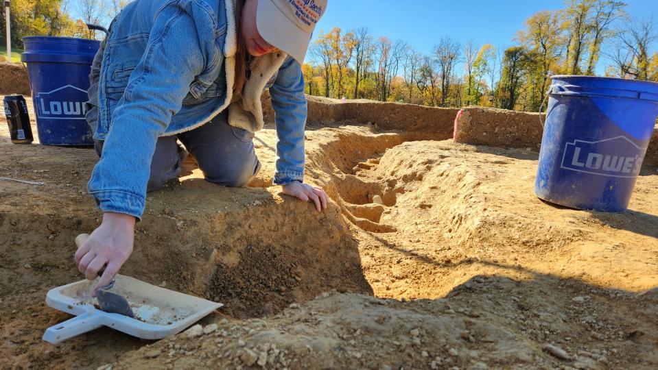 In this photo provided by John Crawmer, Jane C. Skinner excavates post holes at the bottom of the stockade trench, Thursday, Oct. 27, 2022, in York, Pa. Researchers say they have solved a decades-old riddle by finding remnants of the stockade and therefore the site of a prison camp in York, that housed British soldiers for nearly two years during the American Revolutionary War. (John Crawmer via AP)