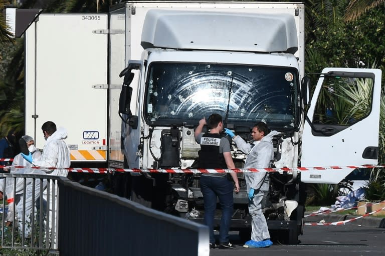 Forensics officers and policemen look for evidence near a truck on the Promenade des Anglais in Nice on July 15, 2016, after it drove into a crowd watching a fireworks display