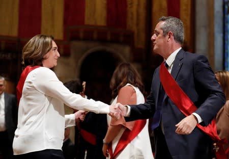 Ada Colau shakes hands with former Catalan Interior Minister Joaquim Forn during her swearing-in ceremony as the new mayor of Barcelona, at Barcelona's town hall