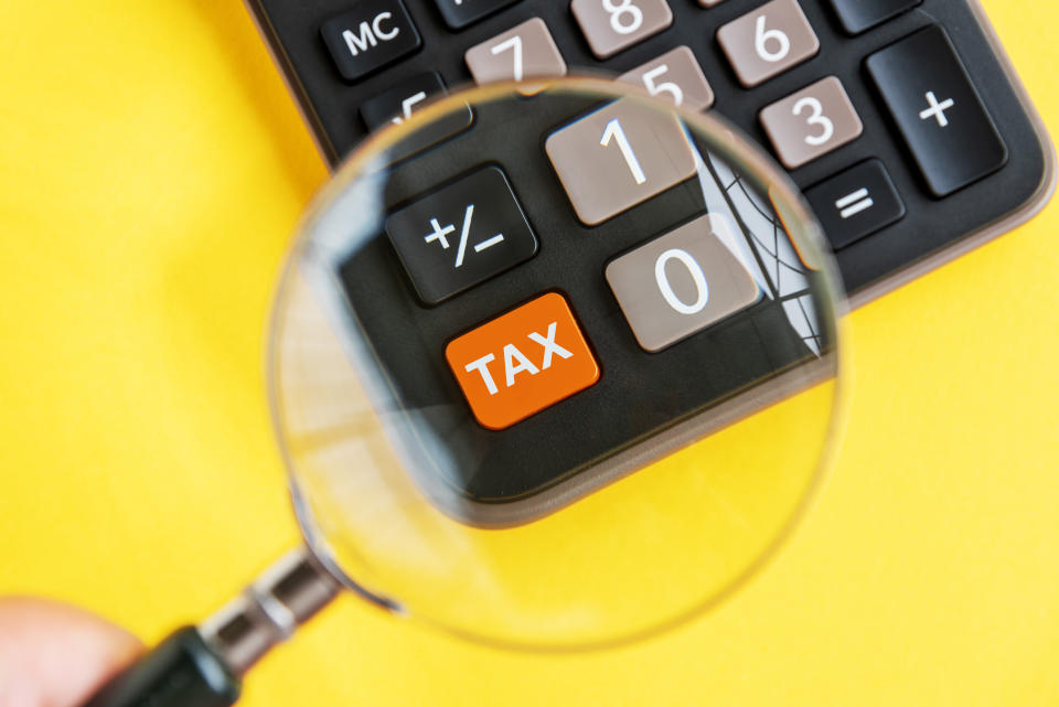 Calculator with the tax button in focus under a magnifying glass, illustrating a story on income tax relief.