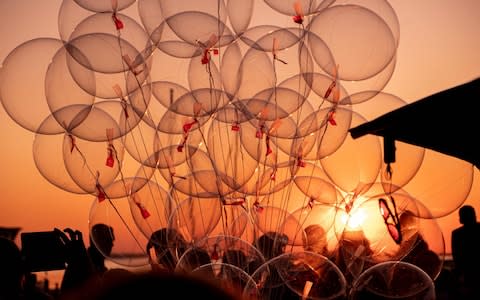 A person holds balloons on the promenade in Steinhude, northern Germany as the sun sets prior to a fireworks display on August 24, 2019. (Photo by Peter Steffen / dpa / AFP) / Germany OUTPETER STEFFEN/AFP/Getty Images  - Credit: PETER STEFFEN/DPA