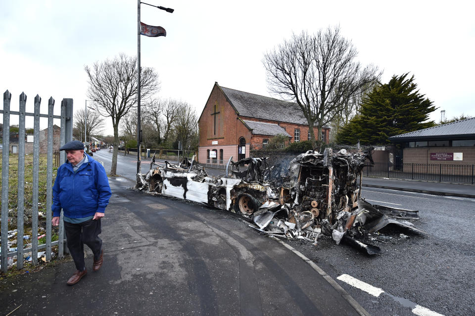 BELFAST, NORTHERN IRELAND - APRIL 08: A man walks past a burnt down bus on April 8, 2021 in Belfast, Northern Ireland. Violence broke out after a Loyalist protest took place in front of the gates of the peace line at the Springfield Road/ Lanark Way Interface. Youths attacked police officers and petrol bombed a bus.  (Photo by Charles McQuillan/Getty Images)