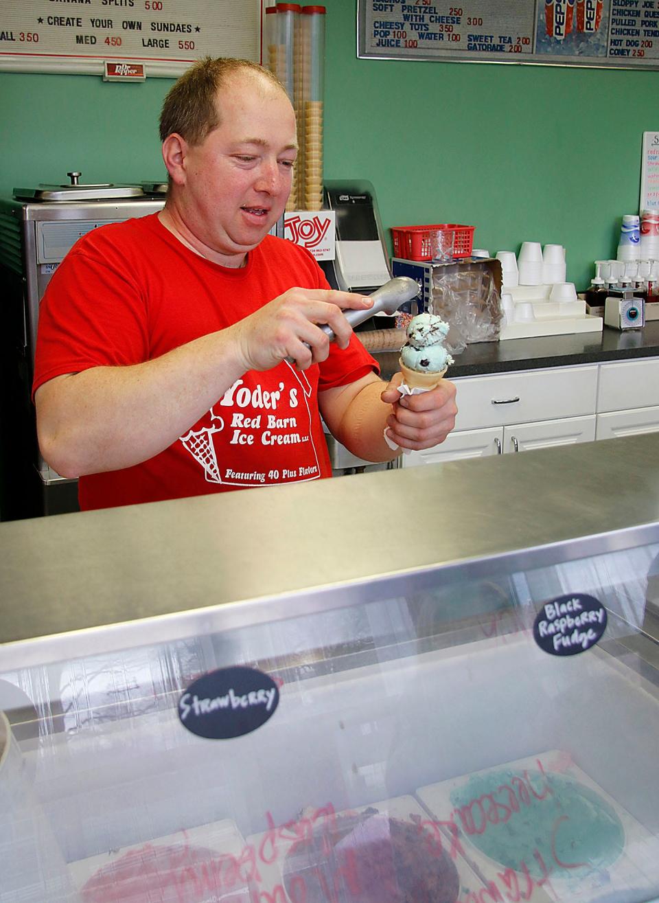 Yoder's Red Barn owner Harley Yoder scoops out a cone for a customer on Thursday, April 7, 2022. TOM E. PUSKAR/TIMES-GAZETTE.COM