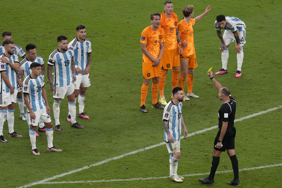 Referee Antonio Mateu shows a yellow card to Argentina's Lionel Messi during the World Cup quarterfinal soccer match between the Netherlands and Argentina, at the Lusail Stadium in Lusail, Qatar, Saturday, Dec. 10, 2022. (AP Photo/Thanassis Stavrakis)