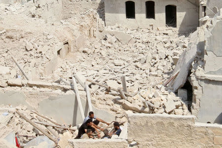 Civil defense members sit amid the rubble of damaged buildings after an airstrike in the rebel held Bab al-Nairab neighborhood of Aleppo, Syria, August 25, 2016. REUTERS/Abdalrhman Ismail