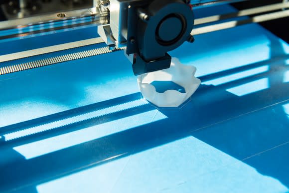 Close-up of a 3D printer printing a white plastic object.