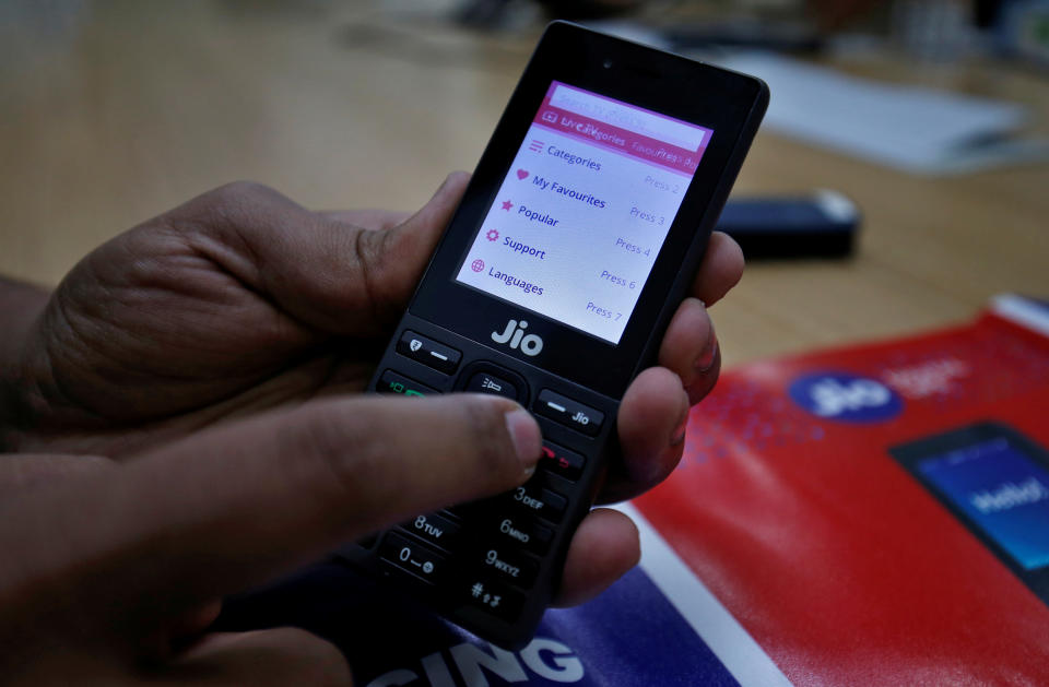 Una persona de ventas muestra las características del JioPhone mientras posa para una fotografía en una tienda de Jio en las afueras de Ahmedabad, India. REUTERS / Amit Dave