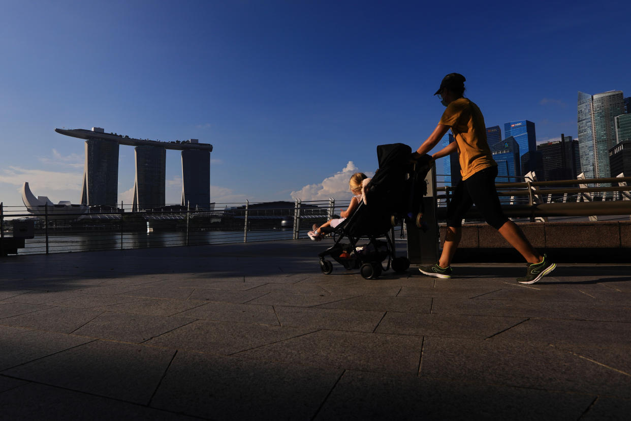 SINGAPORE - MAY 26:  A woman wearing protective mask pushes a stroller with the Marina Bay Sands, ArtScience museum and the central business district pictured in the background on May 26, 2020 in Singapore. Singapore is set to ease the partial lockdown measures against the coronavirus (COVID-19) pandemic after 1 June in three phases to resume activities safely after it sees a decline in the new infection cases in the community. Singapore's gross domestic product (GDP) is expected to shrink as much as 7 percent this year as the country battles the slump in global trade and travel amid the coronavirus pandemic, according to the government report in the local media today.  (Photo by Suhaimi Abdullah/Getty Images)