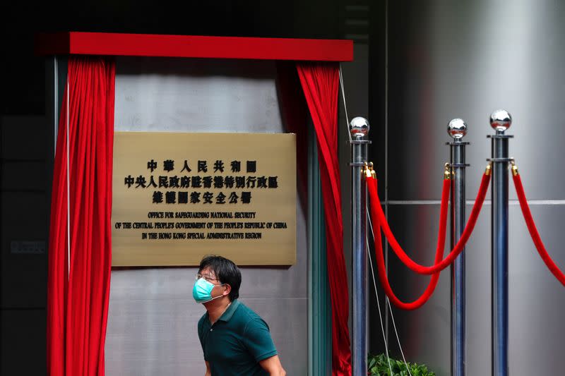 A worker walks past a board after the opening of temporary national security office, in Hong Kong