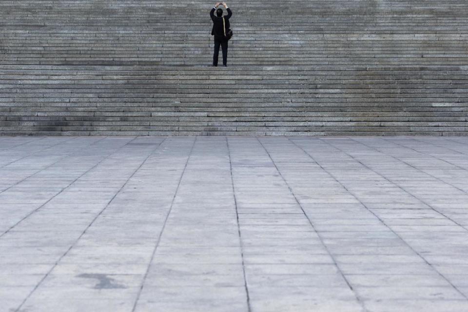 CHANGING SLUG - In this Thursday, March 9, 2017 photo, an attendee takes a photo from the steps of the Great Hall of the People during a plenary session of the Chinese People's Political Consultative Conference in Beijing. Encompassing the area of 24 football fields, the Great Hall of the People where China’s ceremonial legislature and its official advisory body hold their annual sessions is a cavernous edifice that dwarfs the humans who work in it. (AP Photo/Ng Han Guan)