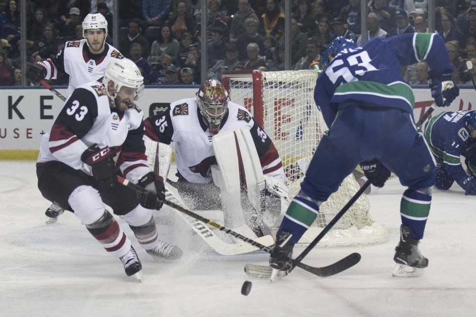 Arizona Coyotes goaltender Darcy Kuemper (35) keeps his eyes on the puck as Coyotes defensemen Alex Goligoski (33) clears the puck from Vancouver Canucks' Bo Horvat (53) during the first period of an NHL hockey preseason game Saturday, Sept. 29, 2018, in Kelowna, British Columbia. (Jeff Bassett/The Canadian Press via AP)