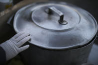 En esta imagen, tomada el 2 de junio de 2020, Natividad Benítez descansa su mano enguantada sobre una olla mientras espera para servir bebidas calientes a gente que vive en la calle, durante la cuarentena ordenada por el gobierno para frenar la propagación del nuevo coronavirus, en la villa 1-11-14, Buenos Aires, Argentina. Argentina, uno de los mayores productores de alimentos, sufre además una creciente emergencia alimentaria. Daniel Arroyo, ministro de Desarrollo Social, dice a la AP que antes de la pandemia 8 millones de personas recibían alimentos, “y hoy tenemos 11 millones”. (AP Foto/Natacha Pisarenko)