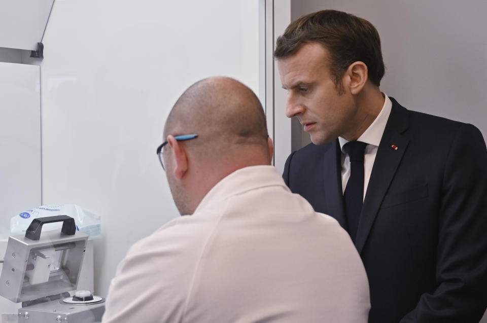 French President Emmanuel Macron speaks to an employee as he visits a plant of British-Swedish pharmaceutical group Astrazeneca in Dunkirk, northern France, Monday, Monday, Jan. 20, 2020. French President Emmanuel Macron is hosting 180 international business leaders later today at the Palace of Versailles in a bid to promote France's economic attractiveness despite over six weeks of crippling strikes over his government's planned pension changes.(Denis Charlet/Pool Photo via AP)