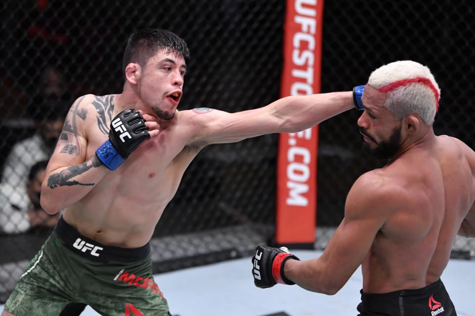 Brandon Moreno (blue) punches Deiveson Figueiredo in their flyweight championship bout during UFC 256. (Photo by Jeff Bottari, Zuffa LLC)