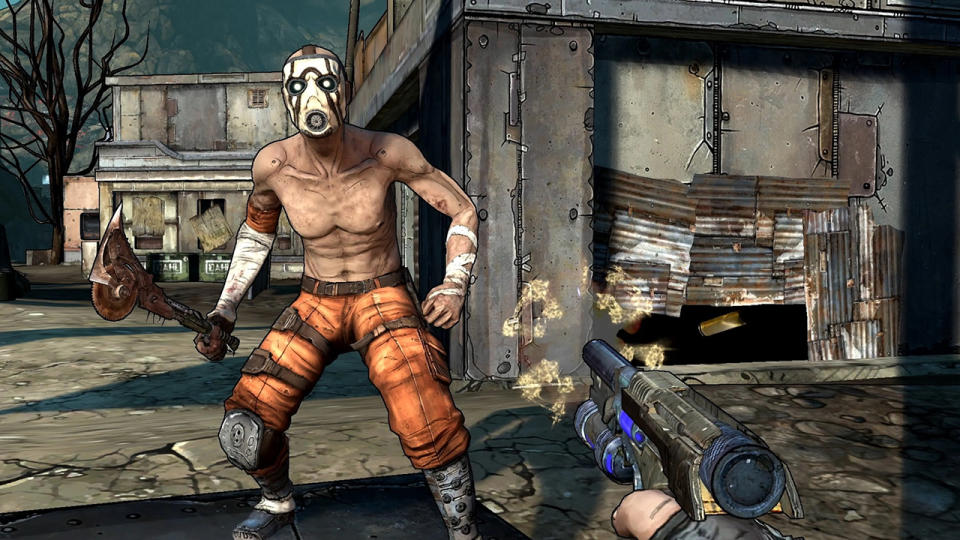 A shot from the Borderlands video game.  You, the player, are pointing a gun at a shirtless man wearing orange pants, a white face mask.  He is wielding a large ax made of nails, a circular saw blade and other debris.  In the background is a shanty town, with houses made of corrugated metal sheets.