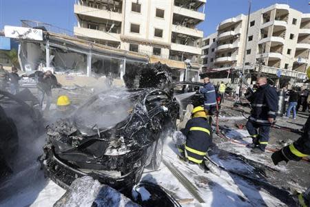Civil defence members put out a fire at the site of an explosion in the southern suburbs of Beirut February 19, 2014. REUTERS/Hasan Shaaban