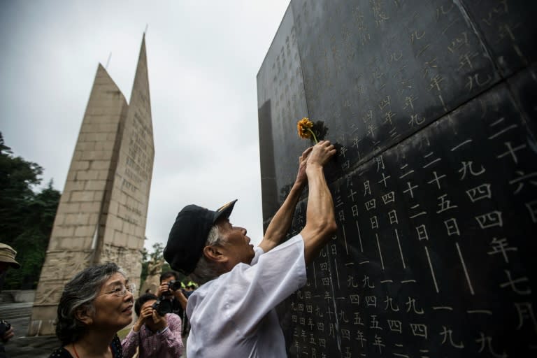 A man places a flower on a monument in Nanjing on March 9, 2014 showing the names of people who died in battles against Japan during World War II