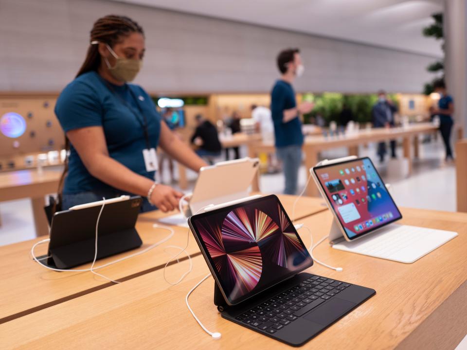 a woman in a blue shirt stands at a table of iPad Pros