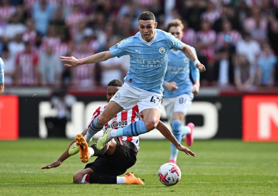 Phil Foden of Manchester City skips away from a challenge by Mathias Jørgensen of Brentford