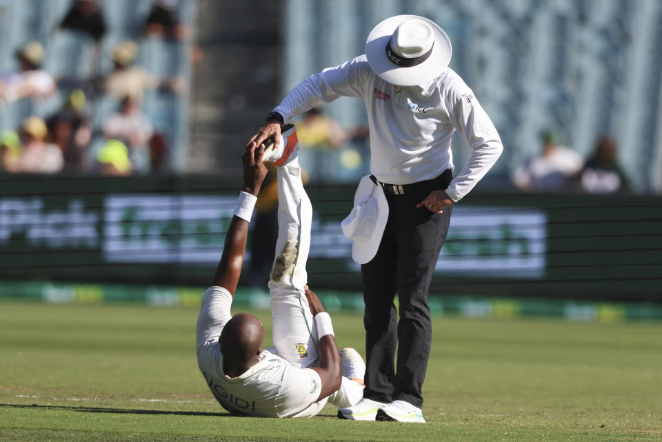 South Africa's Lungi Ngidi is assisted by the umpire as he stretches his leg following cramps during the second cricket test between South Africa and Australia at the Melbourne Cricket Ground, Australia, Tuesday, Dec. 27, 2022. (AP Photo/Asanka Brendon Ratnayake)